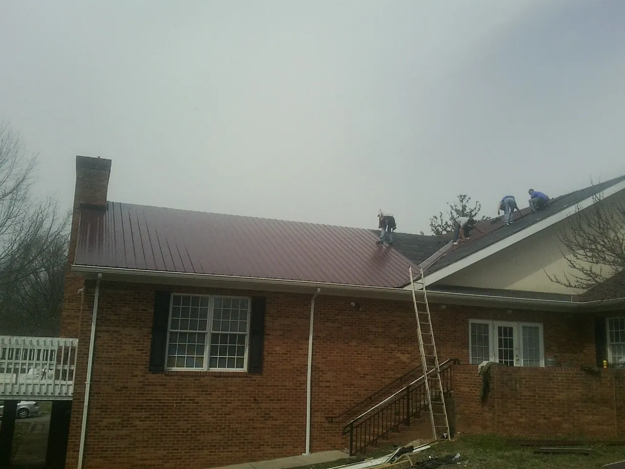 Crew setting red metal roofing panels on a brick home in Clermont