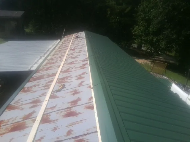 Old rusted panels beside newly installed green metal roofing — Wind Damage Roof Repair by Roofing Brothers in Clermont